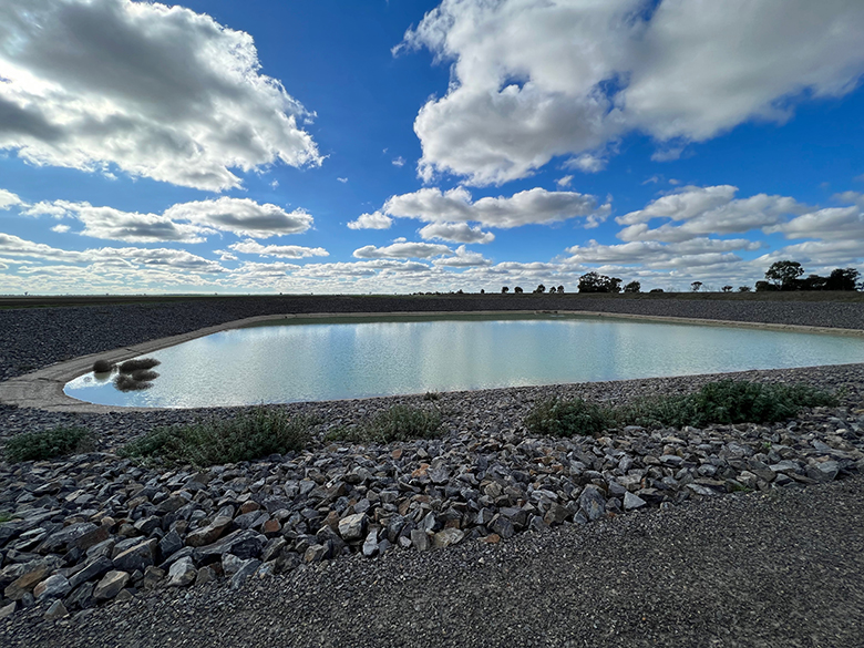 Decorative image - a large dam in rocky soil with a bright cloudy sky overhead