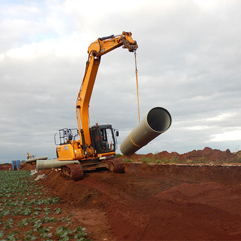 Crane lowering new pipeline into ditch.