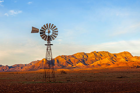 A windmill with the Flinders Ranges behind it in the Australian outback