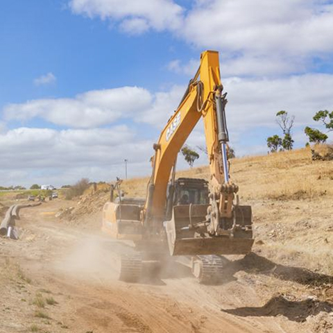 Excavator clearing dry, dusty land.