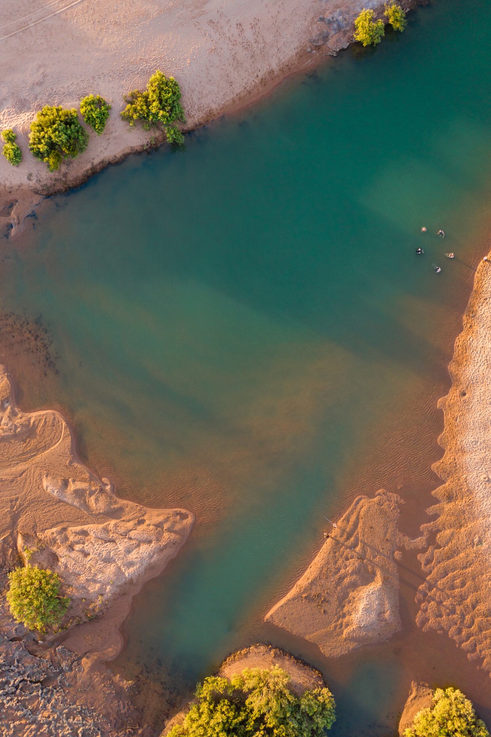 Aerial shot of a natural pool in a red sandy landscape.